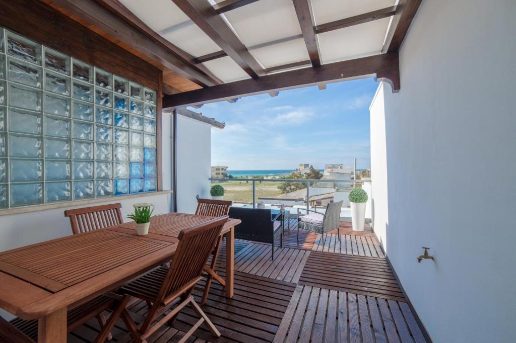 eine Terrasse mit einem Holztisch und Stühlen auf einer Terrasse in der Unterkunft Casa Vacanze Dei Bacini in Porto Cesareo