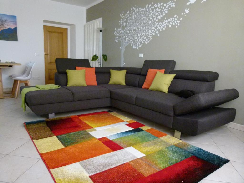 - un salon avec un canapé noir et un tapis coloré dans l'établissement Bed & Bar Mini Apartment, à Pontebba