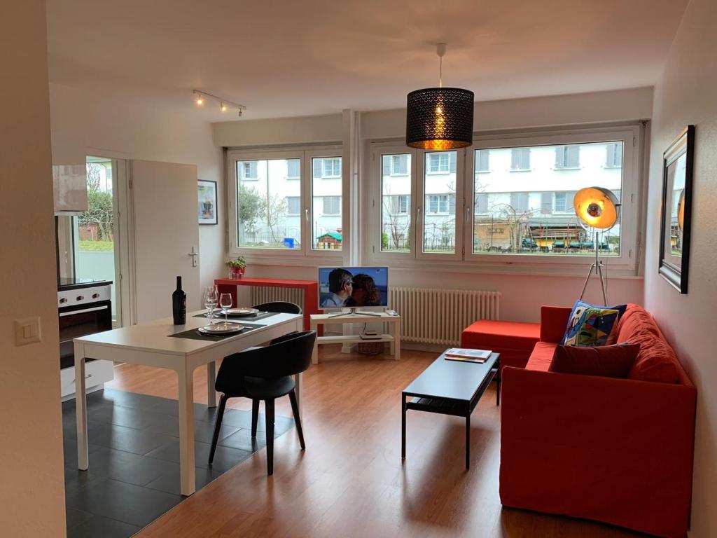 een woonkamer met een rode bank en een tafel bij Geneva Cosy in Genève