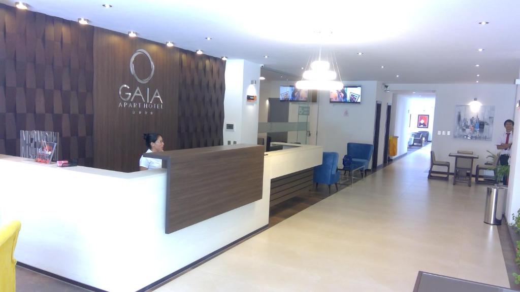 una persona sentada en un mostrador en un vestíbulo en Gaia Apart Hotel, en Tarija