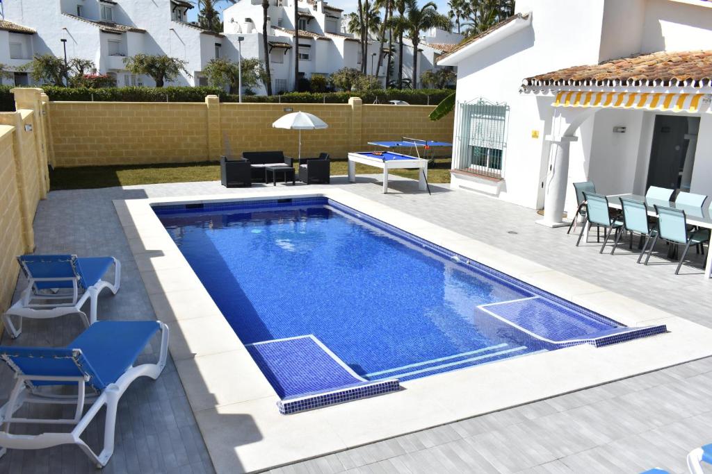 a swimming pool in a backyard with chairs and a table at Villa Esmeralda in Estepona