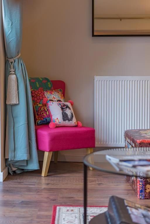 a living room with a pink chair and a glass table at Garden Oasis in Margate