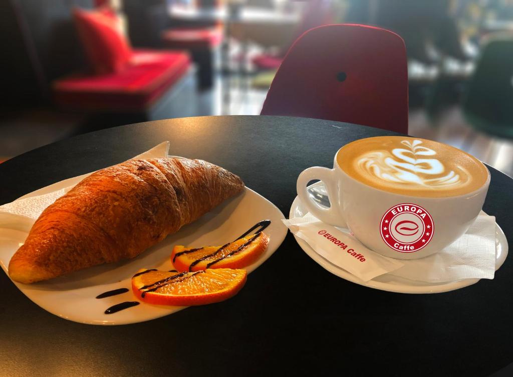 a cup of coffee and a croissant on a table at Europa Apartment in Tirana