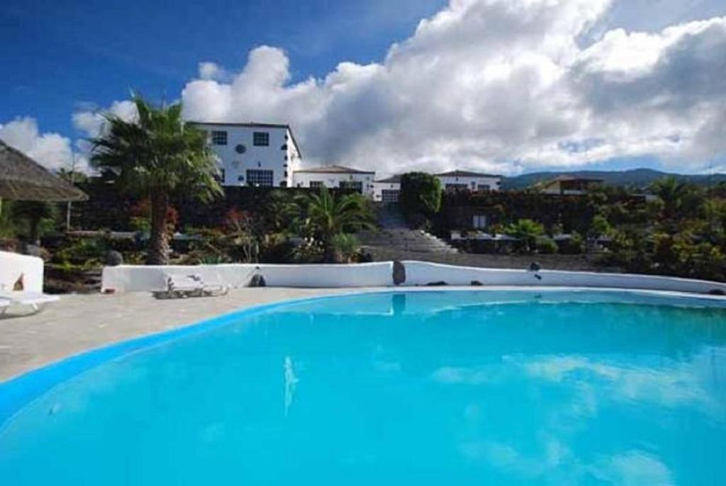 una gran piscina azul frente a una casa en La Hacienda BuenVivir - Apartamentos, en Los Llanos de Aridane