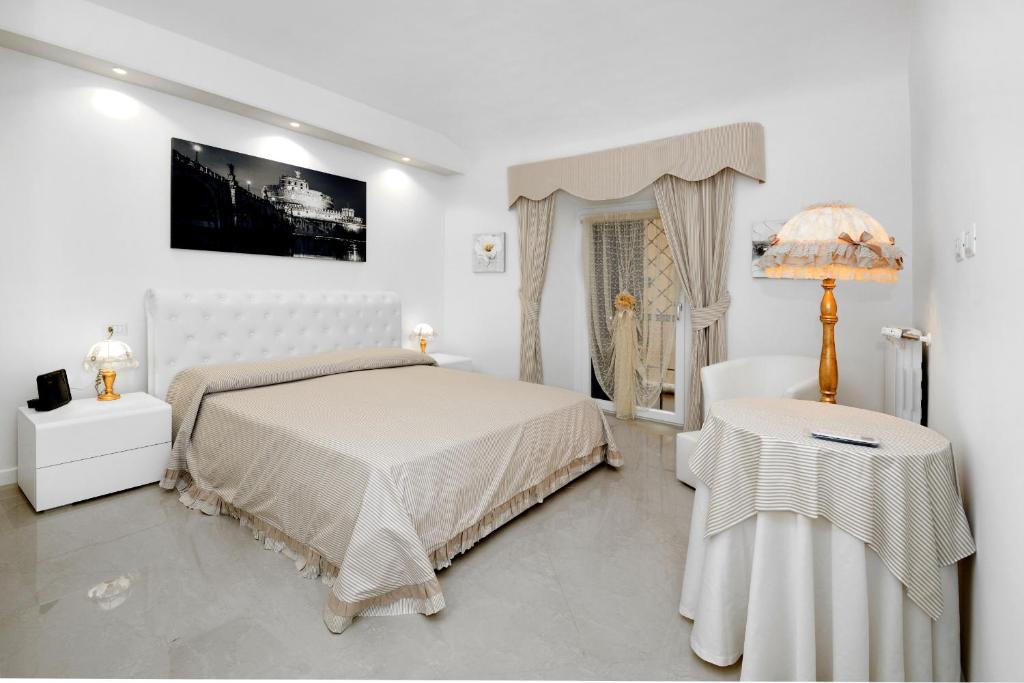 ein weißes Schlafzimmer mit einem Bett und einem Tisch in der Unterkunft Ludovisi Barberini Grand Apartment in Rom