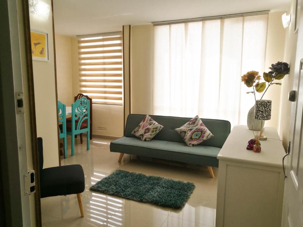 een woonkamer met een blauwe bank en een raam bij Aparta hotel TOCANCIPA con Parqueadero y Wifi in Tocancipá