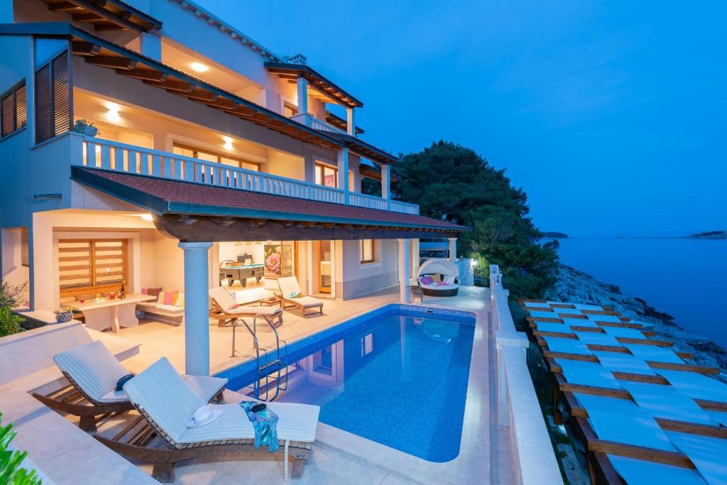 a villa with a swimming pool and a house at Exceptional Beachfront Holiday Villa on Korčula Island in Prizba