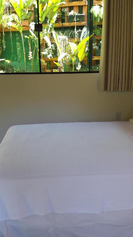 a white bed in a room with a window at venha curtir a natureza in Nova Friburgo