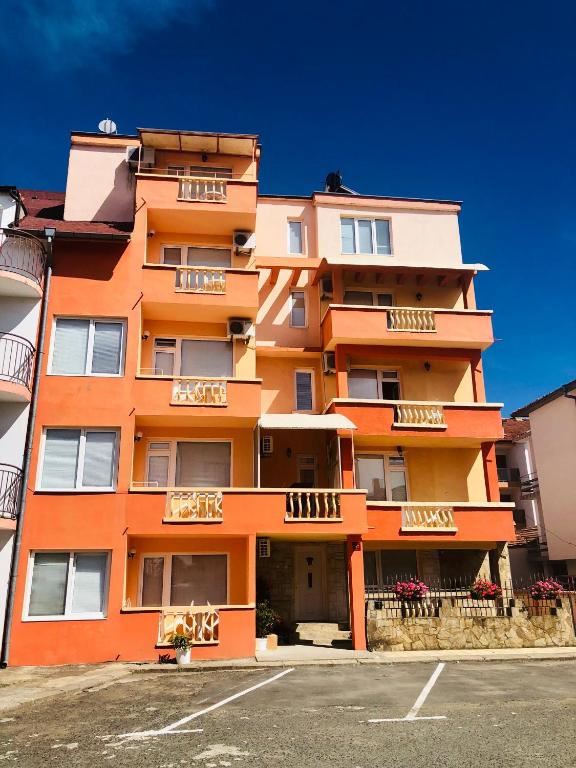 an orange apartment building with a parking lot at Guest House Rai in Kiten