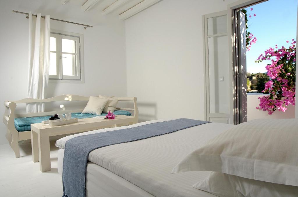 a white bedroom with a bed and a window at Kapetan Tasos Suites in Pollonia