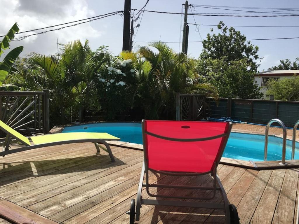 a red chair sitting on a deck next to a pool at Sunshine Villa in Le Moule