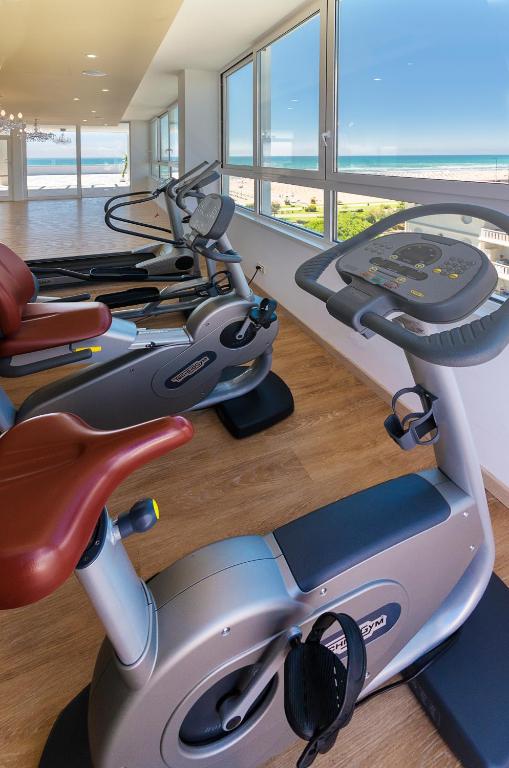 a gym with a treadmill in a room with windows at Hotel Montecarlo in Bibione