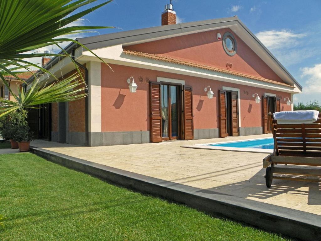 a house with a pool and a bench in front of it at VILLA VITTORIA in Pedara