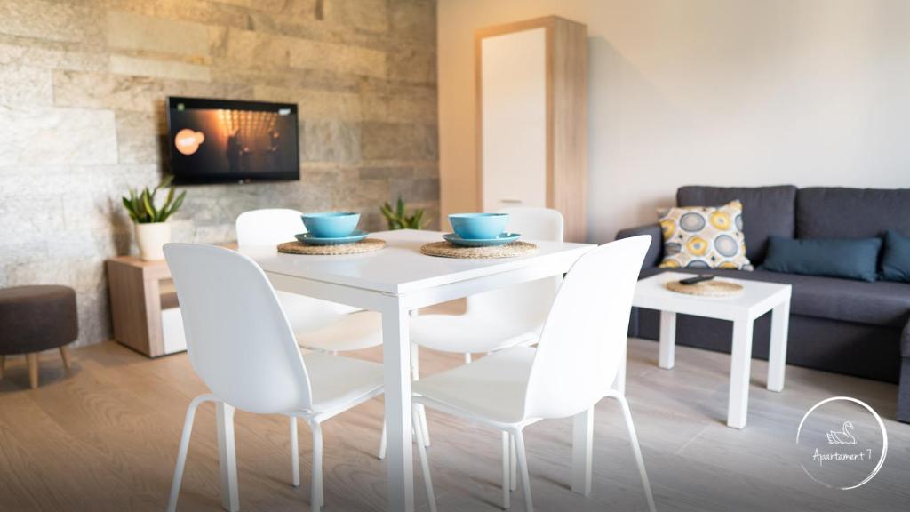 Apartament Siódemka في بيش: طاولة طعام بيضاء وكراسي في غرفة المعيشة