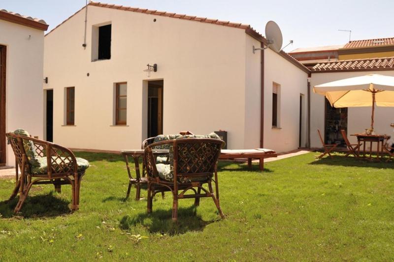 dwa krzesła i stół i parasol na dziedzińcu w obiekcie Lanita B&B w mieście Cabras