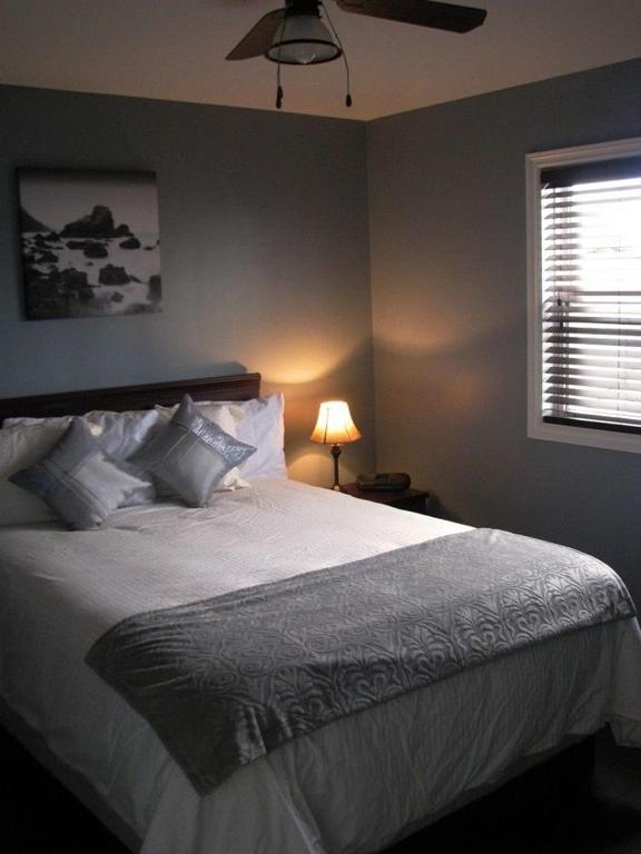 een slaapkamer met een groot wit bed en een plafondventilator bij Stay in Gros Morne in Rocky Harbour