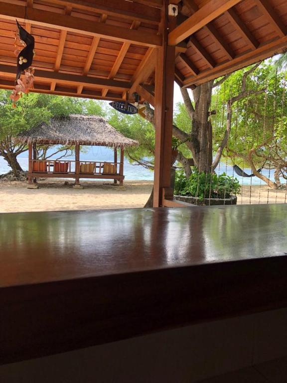 a table in a pavilion with a bench in the background at Biru Meno Beach Bungalows in Gili Meno
