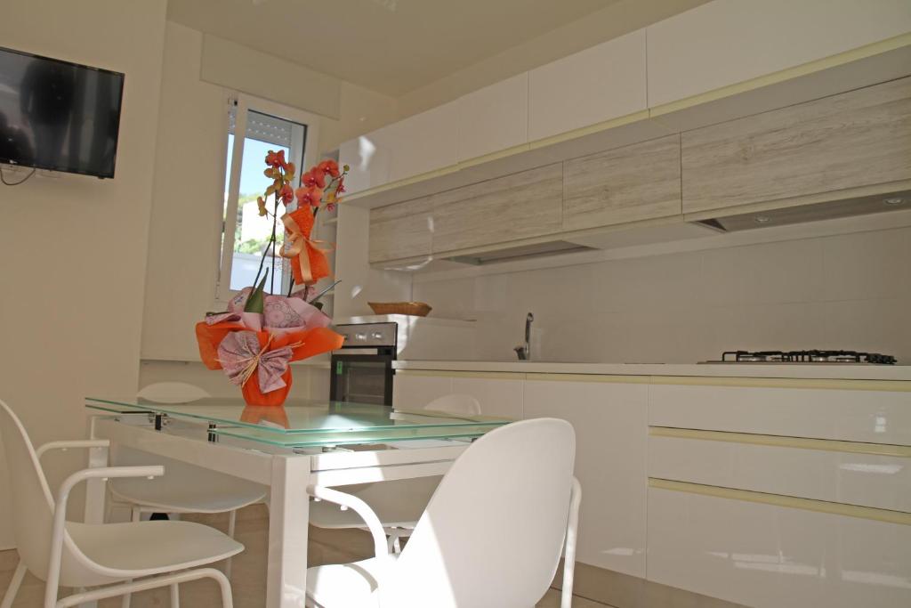 une cuisine avec une table en verre et des chaises blanches dans l'établissement Grotta Verde, à Andrano