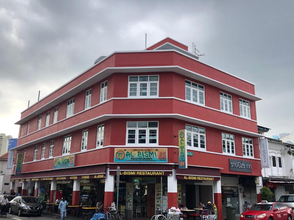 a red building on a street with cars parked in front at Snooze Inn @Dickson Road in Singapore