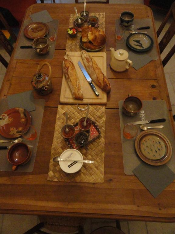 a wooden table with plates of food on it at Les chambres de Blanot in Blanot
