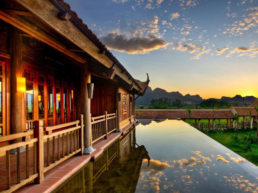 a reflection of a building in the water at sunset at Emeralda Resort Ninh Binh in Ninh Binh