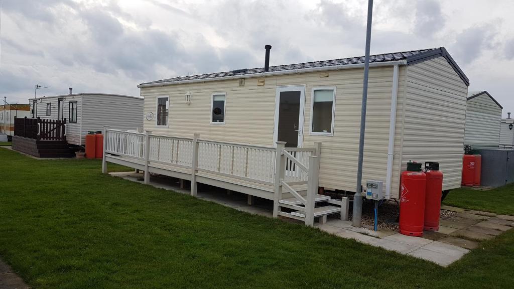 a white mobile home with a porch and a fire hydrant at Silver beach 3 in Ingoldmells