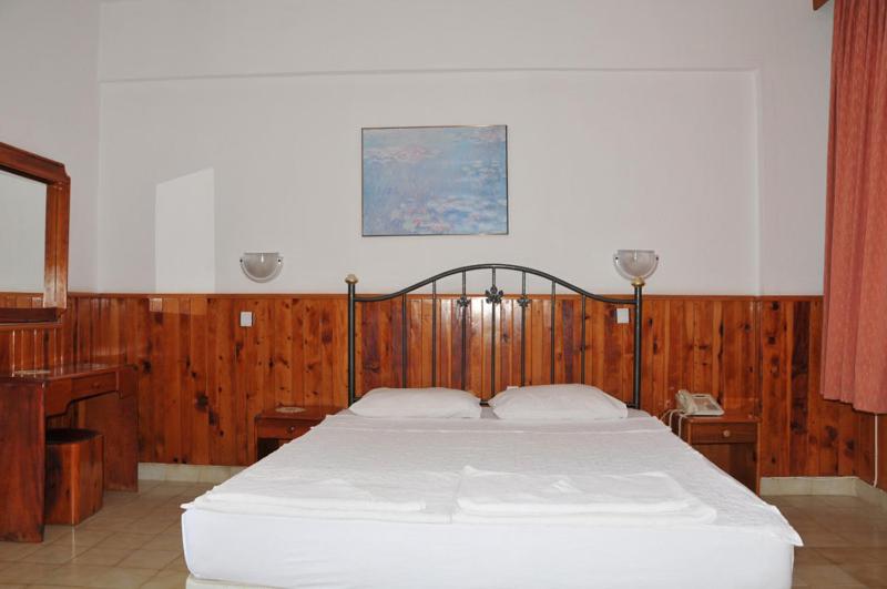 1 dormitorio con 1 cama blanca y paredes de madera en Hotel Royal, en Alanya