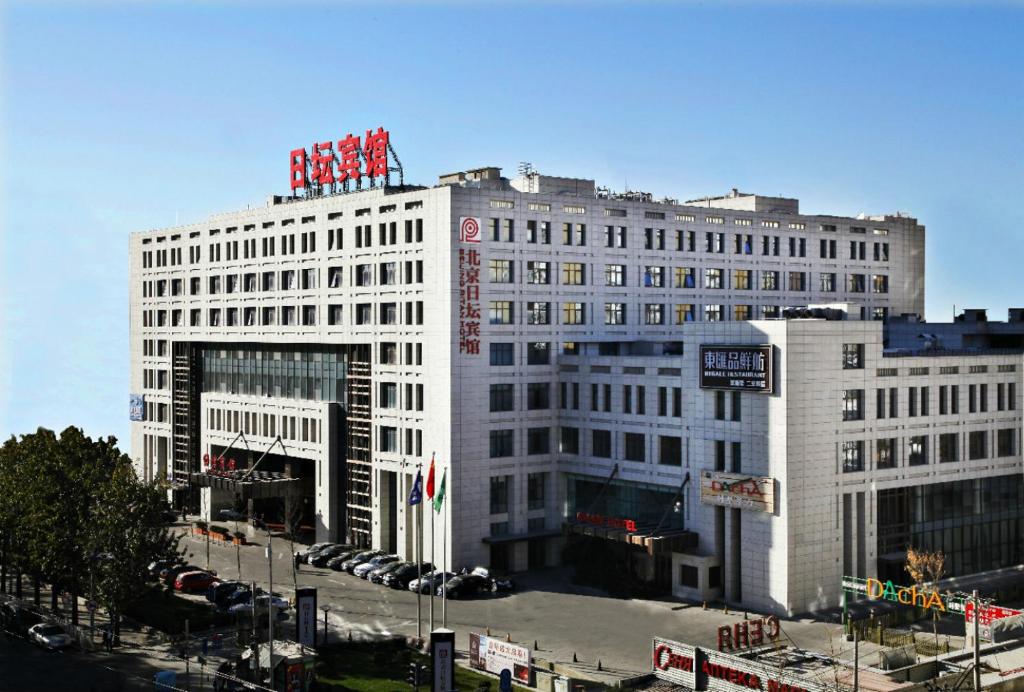 un gran edificio blanco con un grupo de señales rojas en la parte superior en Ritan Hotel Downtown Beijing, en Beijing