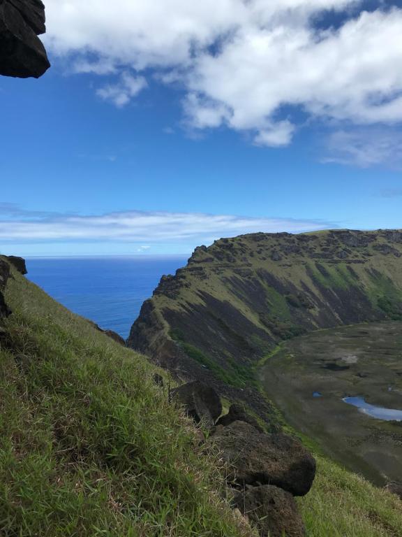 a grassy hill with the ocean in the background at Inaki Uhi Hotel in Hanga Roa