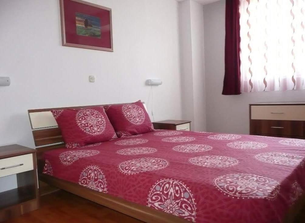 a bedroom with a bed with red sheets and a window at Mario in Ohrid
