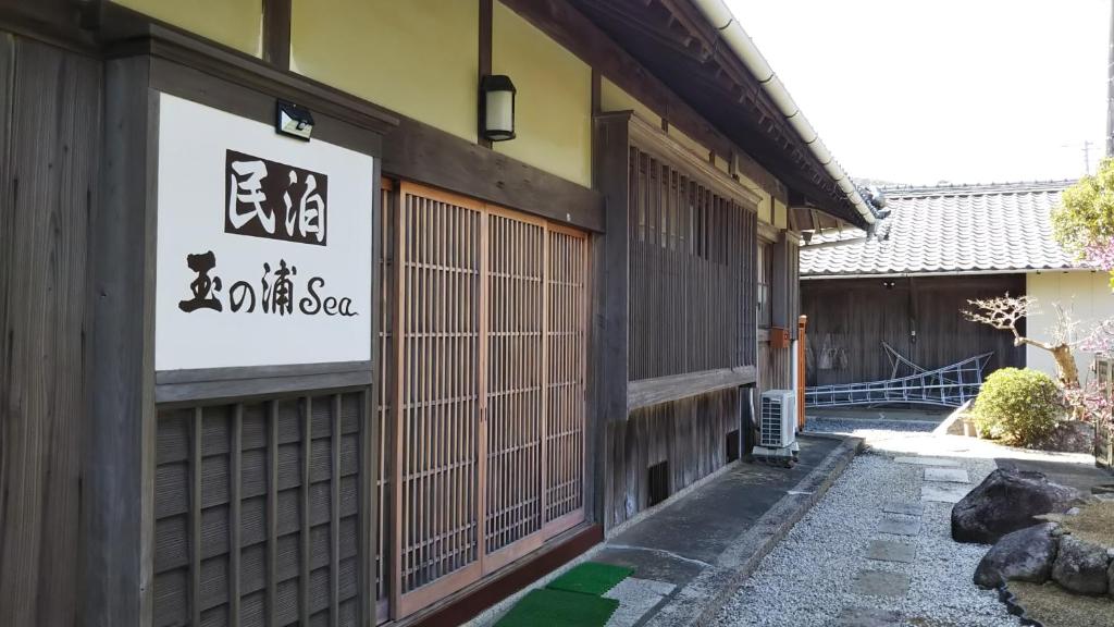 un edificio con una puerta y una señal en él en 玉の浦sea, en Nachikatsuura