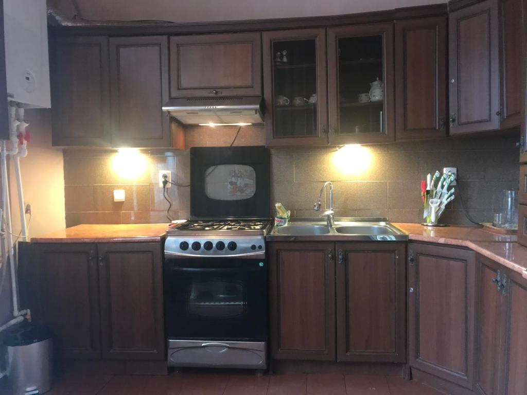 a kitchen with wooden cabinets and a stove and a sink at Gamsakhurdia Street in Borjomi