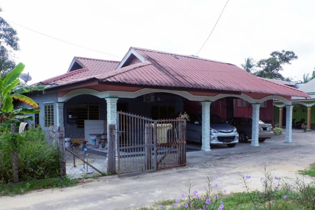 a house with a red roof and a gate at Homestay Tok Abah Kuala Rompin 1 Bilik Tidur in Kuala Rompin