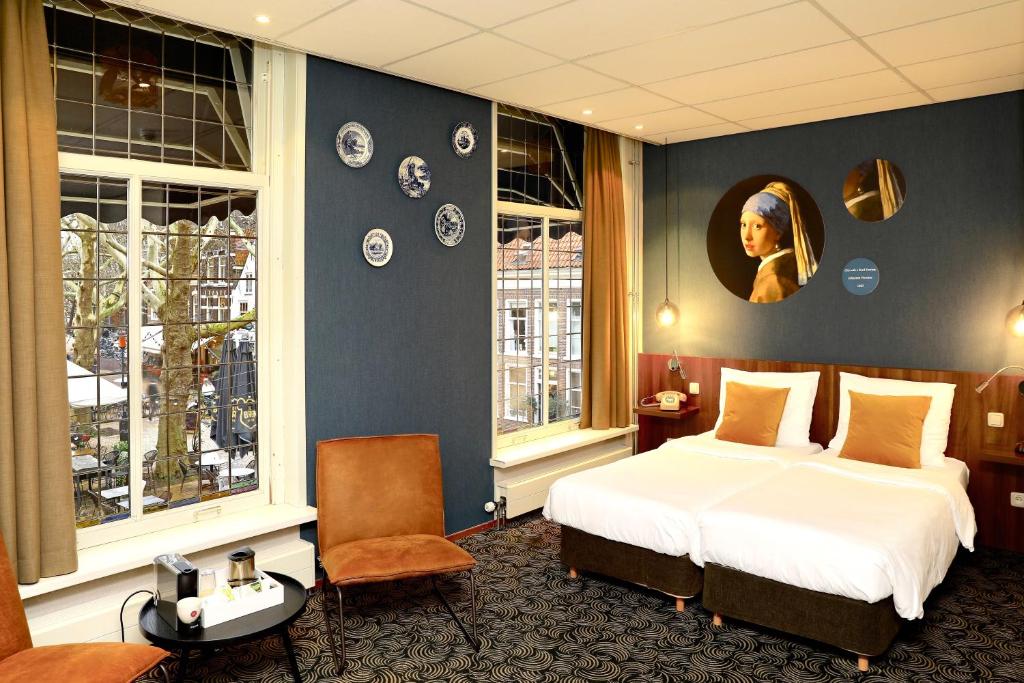 een hotelkamer met een bed en twee ramen bij Hotel de Koophandel in Delft