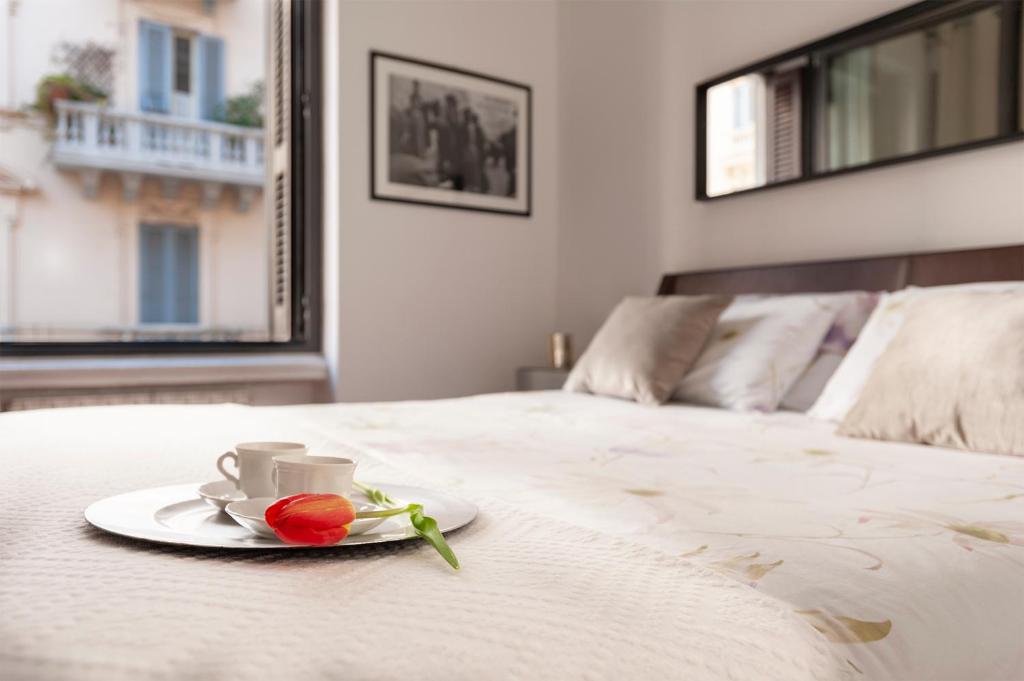 talerz z kubkiem i kwiat na łóżku w obiekcie Via Bozzi Luxury Home w mieście Bari
