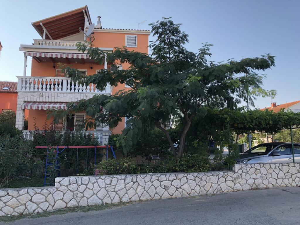 a house with a tree in front of a wall at Apartments Stancic in Vodice