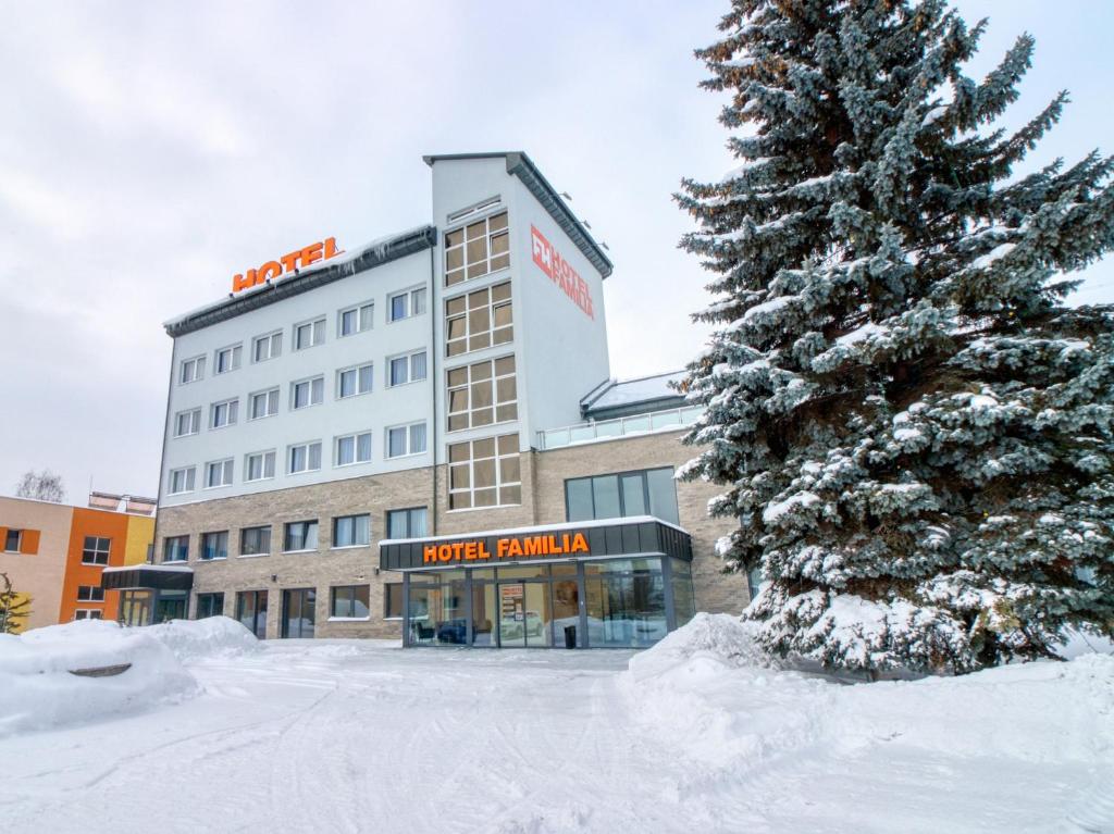 a snow covered tree in front of a hotel at Hotel Familia in Stará Ľubovňa