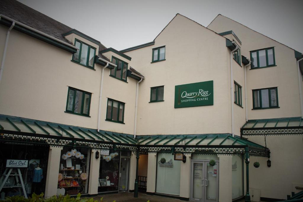 a large white building with a green sign on it at Darcey's Apartment in Bowness-on-Windermere