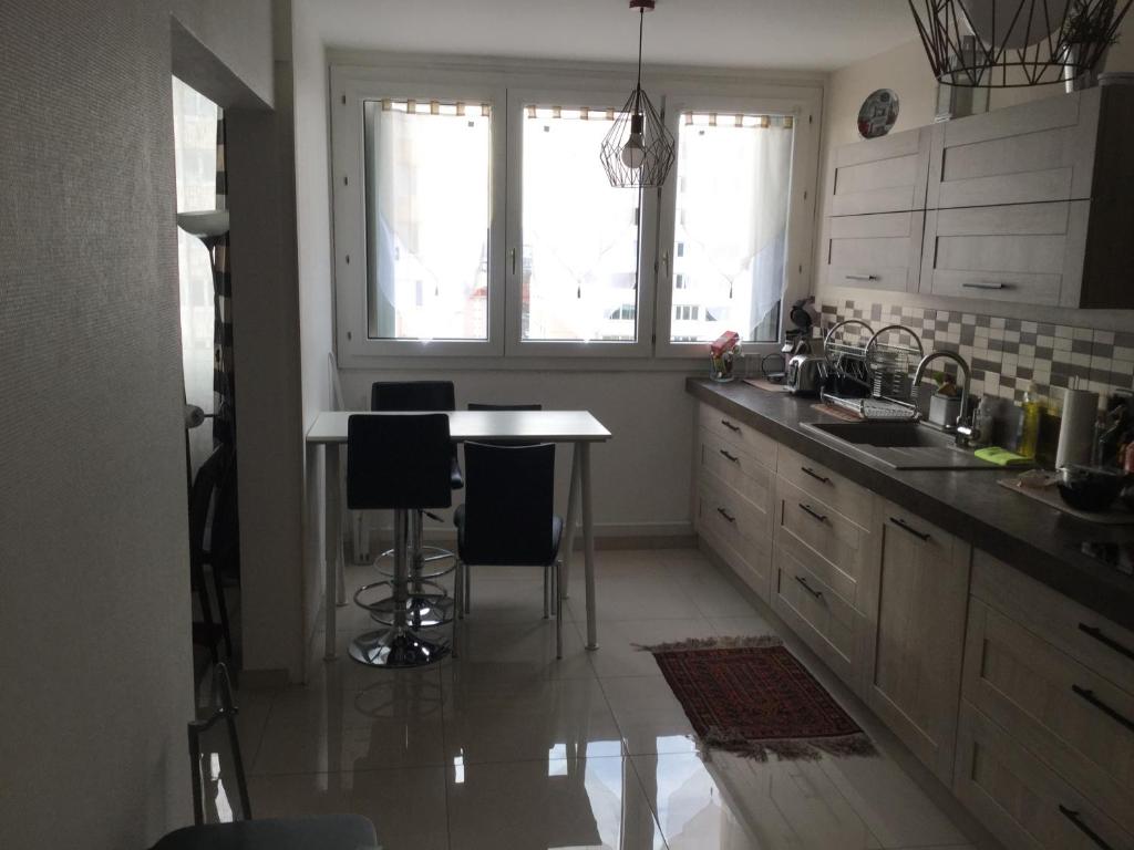 una cucina con tavolo, sedie e finestra di Appartement Laurent Bonnevay a Villeurbanne