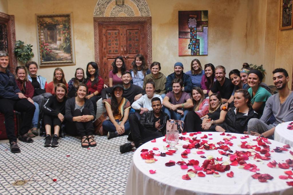 un grupo de personas sentadas alrededor de una mesa con rosas en Hostel Dream belko en Marrakech
