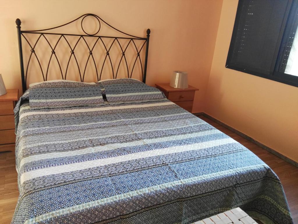 a bed with a blue and white blanket on it at Donde Brilla el Sol in Candelaria
