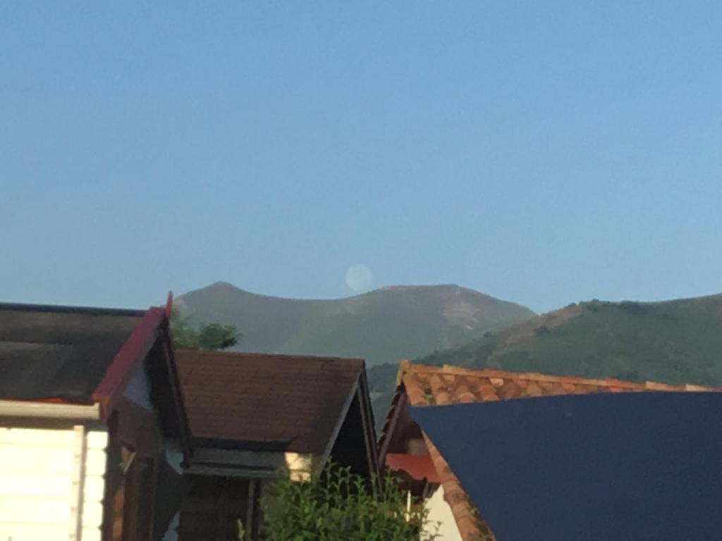 a view of some buildings with mountains in the background at Maison Fleurie in Uhart-Cize