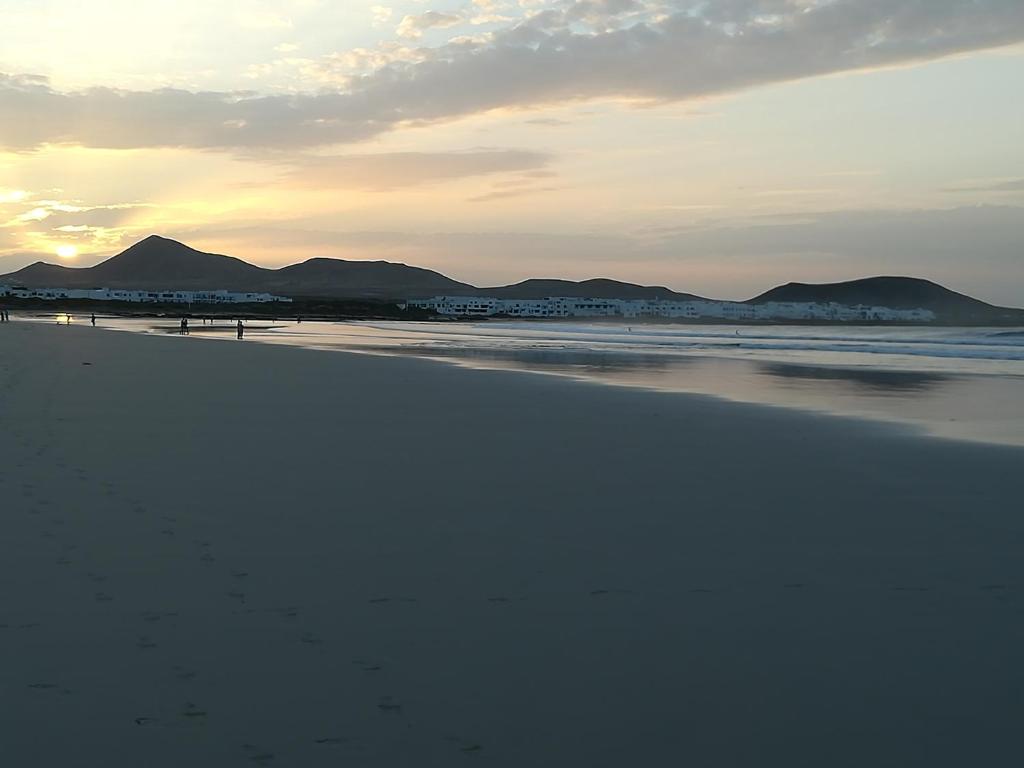 a beach with mountains in the background and the ocean at El Charquito in Famara