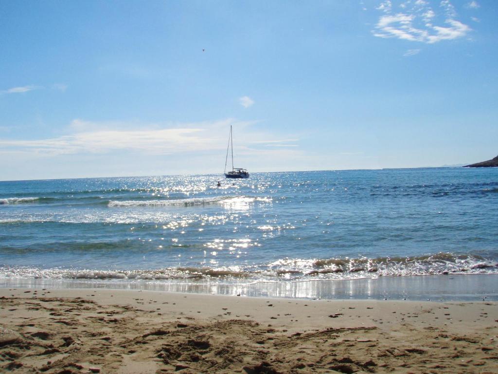 a sail boat in the ocean with a beach at ECO Aparthotel The Dreamers's Club in Lumbarda