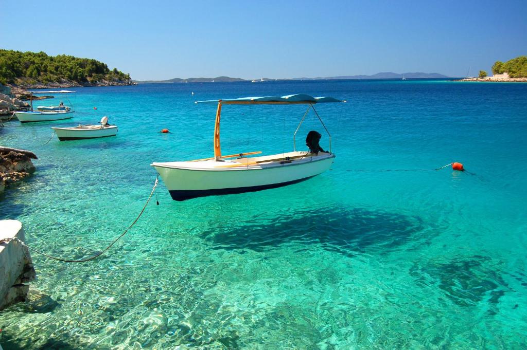 a boat in a body of water with other boats at ECO Aparthotel The Dreamers's Club in Lumbarda