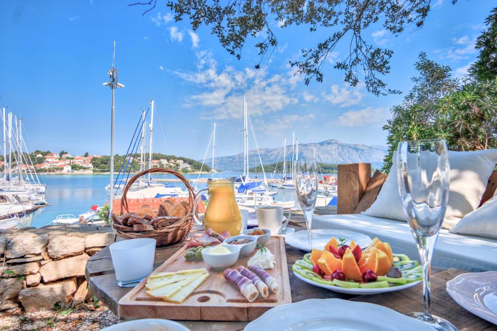 a table with food and wine glasses and a view of a harbor at ECO Aparthotel The Dreamers's Club in Lumbarda