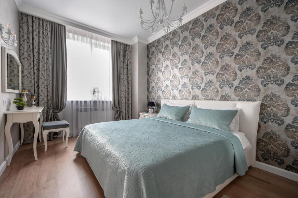 a bedroom with a large bed with a blue blanket at Arkadia Plaza Design Apartment in Odesa