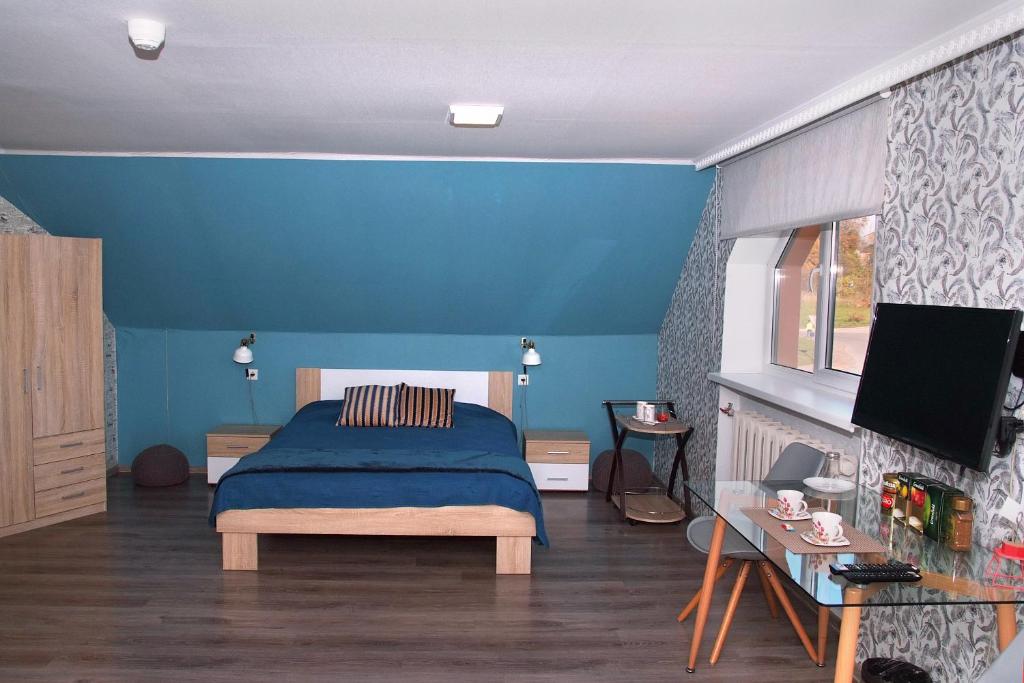 Central Riverside Apartments في جيكاببيلس: غرفة نوم زرقاء مع سرير وتلفزيون بشاشة مسطحة