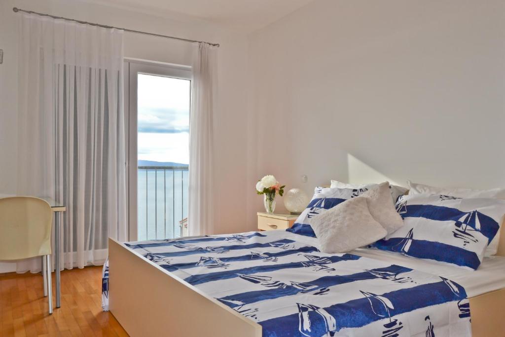 een slaapkamer met een blauw en wit bed en een raam bij Studio Berni in Stanići