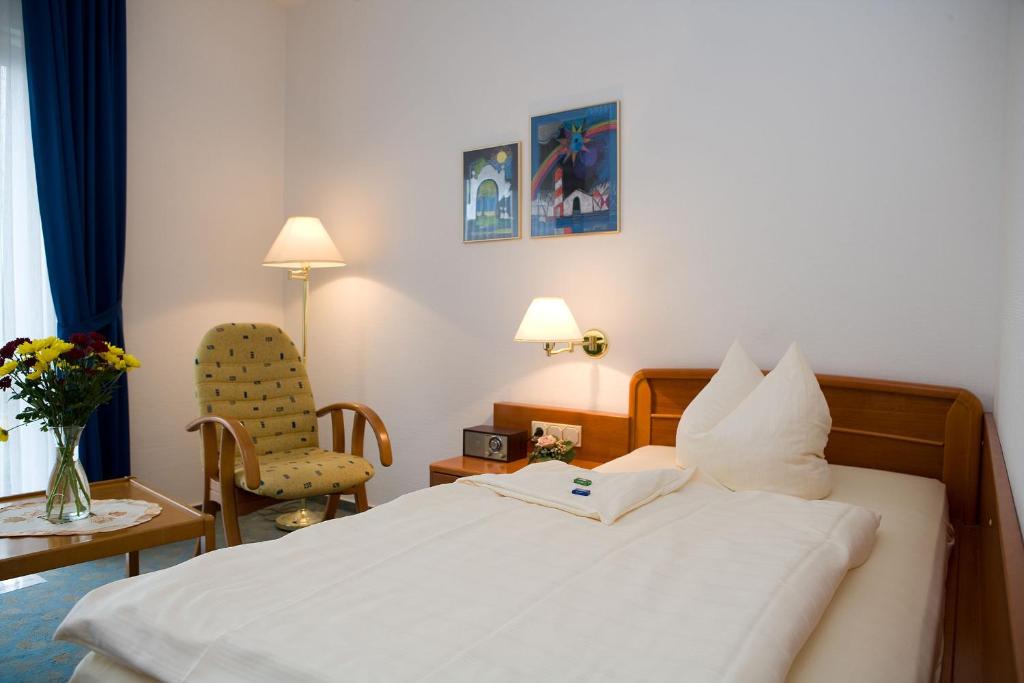 um quarto de hotel com uma cama e uma cadeira em Central Inn Hotel garni em Eppelborn